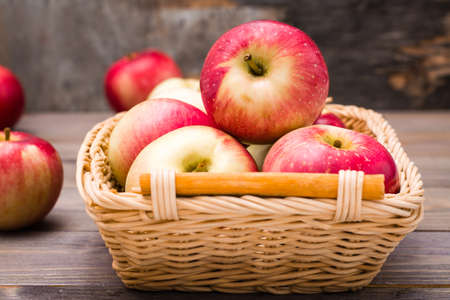 Fresh harvest of apples. Nature theme with red apples in a basket on a wooden backgroundの写真素材