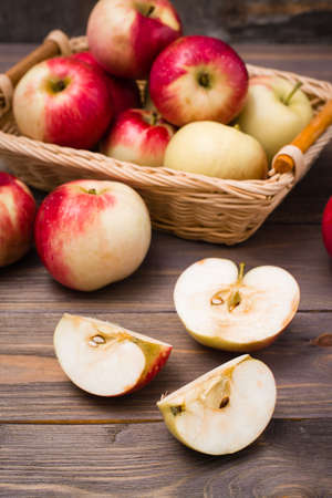 Sliced apple and ripe red apples on a wooden table and in a basketの写真素材