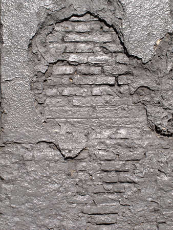 Old gray wall with exposed brick, lots of texture.の写真素材