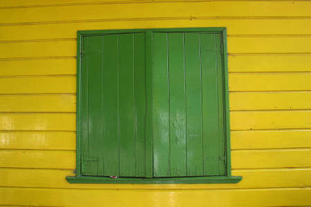 A closed green window on a wooden wall yellowの写真素材