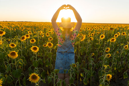 Ukraine. summer evening. Girl with a hat in a field with sunflowersの写真素材