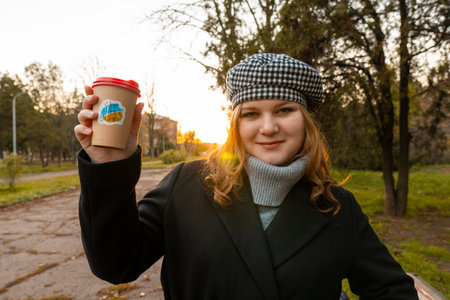Ukraine. Evening. Sunset. city park. End of the working day. The girl holds in her hands a cup of...