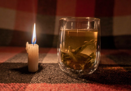 blackout. energy crisis. Destruction of infrastructure. power outage concept. A transparent cup of herbal tea by the light of a burning candle. close-upの写真素材