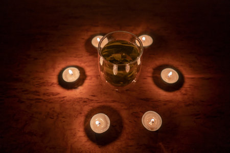 Transparent cup of herbal tea stands in a circle of burning candles (close-up). power outage concept. blackout. energy crisis. Destruction of infrastructureの写真素材