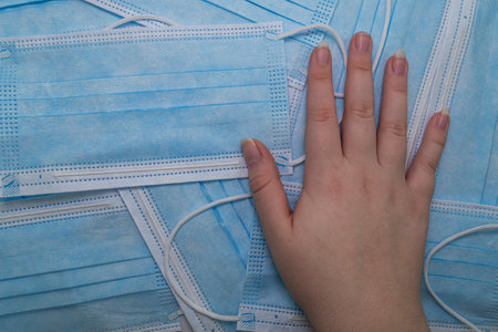 The human palm lies on blue medical masks (top view). Disposable surgical face mask. Protection against coronovirus Covid-19, pollution and infectionsの写真素材