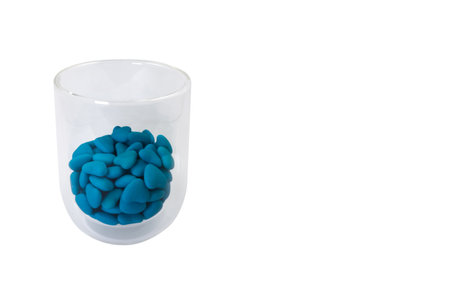 Glass with heart shaped blue candies (close-up) isolated on white backgroundの写真素材