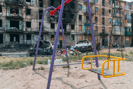 An empty children's playground next to a residential building destroyed by rocket fire. War in Ukraine. Terror of the civilian populationの写真素材