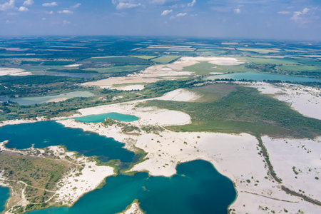 Top view of flooded quarries with white quartz sand. Beautiful artificial lakes with blue water....