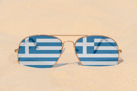 Sunglasses with glasses in the form of the flag of Greece lie on the sand. The concept of summer holidays, travel and tourism in Greece. Summer rest. holiday seasonの写真素材