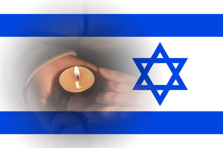 A burning candle in hands against the background of the Israeli flag. Israeli-Palestinian conflict. Terror of civiliansの写真素材