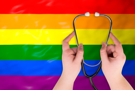 Female hands holding a stethoscope on the LGBT flag background.の写真素材