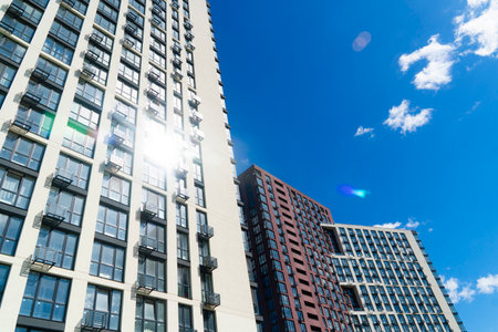 Tall, modern high-rise residential buildings with many windows and balconies on a sunny day with a...