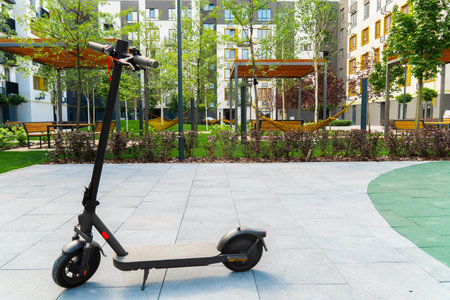 Modern electric scooter parked on a paved area in the landscaped courtyard of a residential complex...