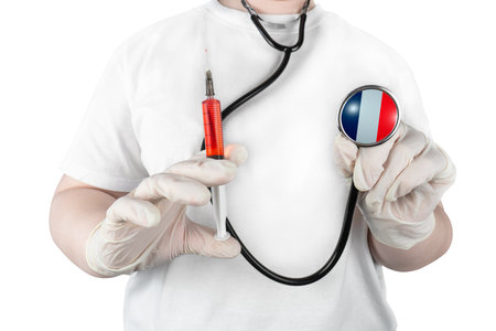 A doctor on a white background holds a syringe with red liquid and a stethoscope with the national flag of France depicted on the membrane, symbolizing French healthcareの写真素材