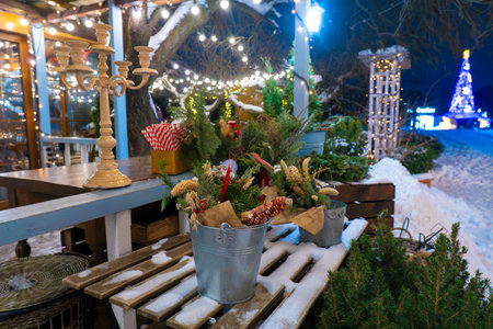 Winter holiday decorations on a wooden terrace with a vintage candelabra, fir branches and glowing lights at night. Snowy seasonal atmosphere outdoorsの写真素材