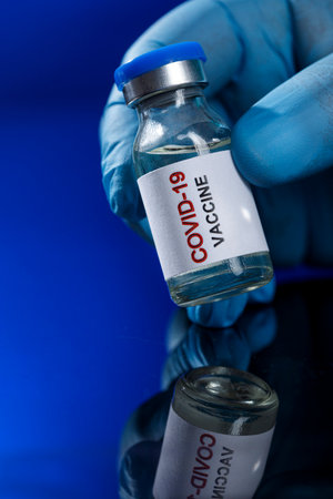 Coronavirus COVID-19 vaccine bottle with syringe on blue backgroundの写真素材