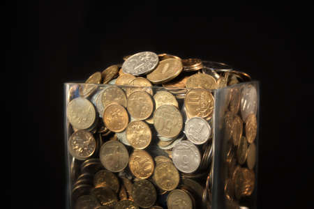 Coins in a glass jar on a black background