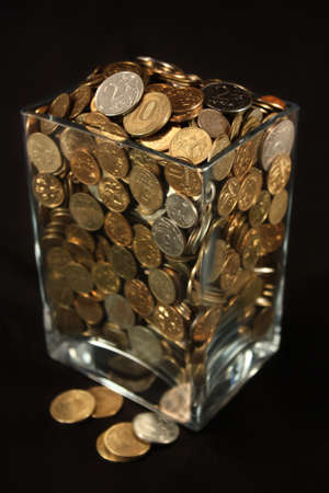 Coins in a glass jar on a black background