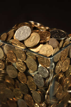 Coins in a glass jar on a black backgroundの写真素材