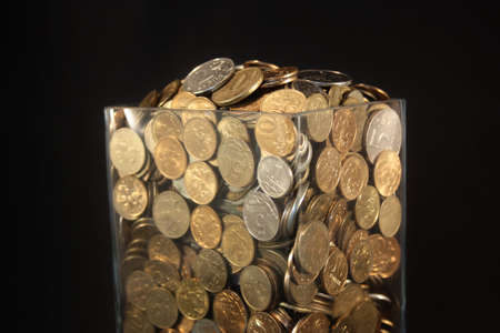 Coins in a glass jar on a black backgroundの写真素材