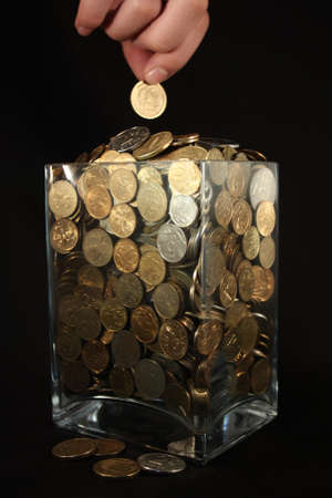 Coins in a glass jar on a black background