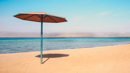 Beach side rest chairs and umbrellas on the sand near the blue water and horizon