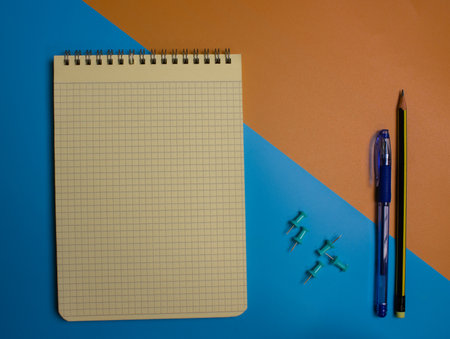Top view of an open notebook with a pencil and an eraser on a white and yellow background.の写真素材