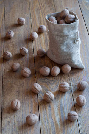 Walnuts in a cotton bag on a wooden table.の写真素材