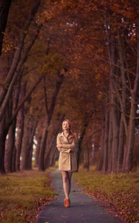 beautiful young woman on the road among the autumn treesの写真素材