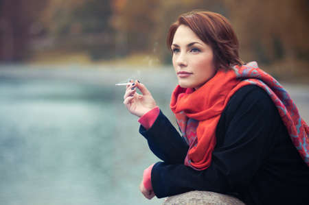 pretty girl smoking in autumnの写真素材