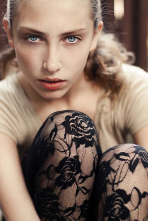 portrait of beautiful girl sitting on a city streetの写真素材