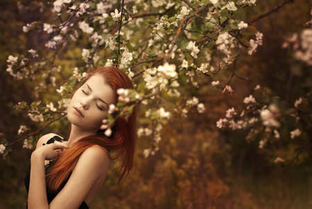 beautiful redheaded woman in a spring gardenの写真素材