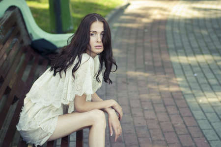 Beautiful girl sitting on a benchの写真素材