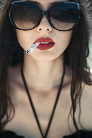 beautiful brunette with glasses smokingの写真素材