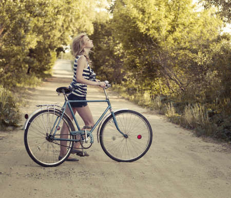 beautiful smiling girl with a bicycle on the road