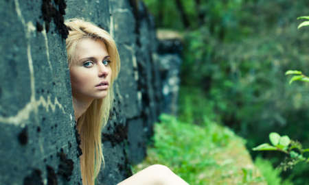 beautiful girl looks out from behind the wallの写真素材