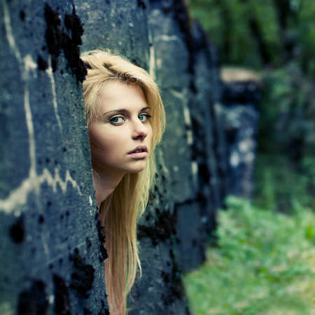 beautiful girl looks out from behind the wallの写真素材