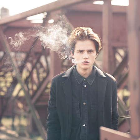 Trendy young man smoking outdoors の写真素材