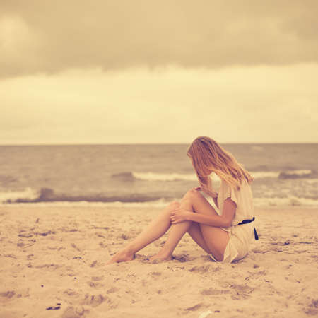beautiful girl sitting on the shore of the ocean の写真素材