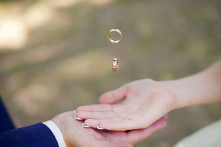Bride's and groom's hands with flying ringsの写真素材
