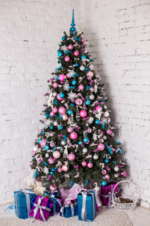Decorated Christmas tree on white background with blue, silver and pink decorations, snowflakes ang gifts. Cold colors. Studio vertical colorful photoの写真素材