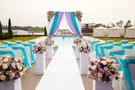 Beautiful romantic wedding arch set up decoration on wedding ceremony in blue, cyan, purple, magenta colors. With flowers and clothの写真素材