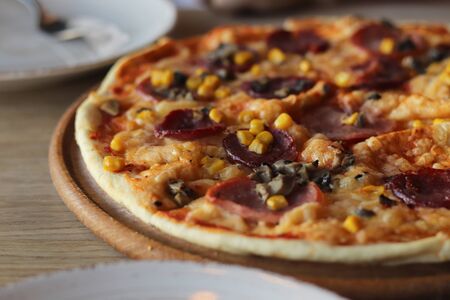 Tasty hot pizza on a wooden plate. Cutlery. Food in cafe.の写真素材