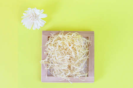 Cardboard, organic box filled with shredded paper on a yellow background top view. Holiday card....