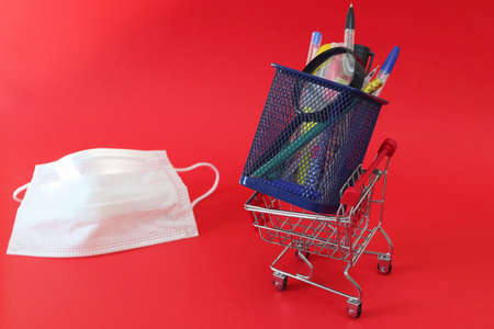 Blue stationery stand. Defocused medical mask on a red background. Copy space - study concept,...