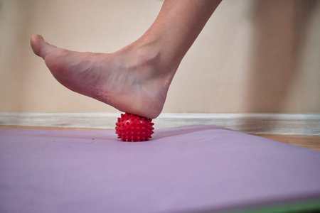 A heel resting on a small massage ball, demonstrating foot therapy, muscle relief, and relaxation. Perfect for self-massage and recovery exercises.の写真素材