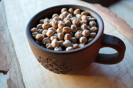 chick-pea in a clay bowl on  wooden background in beams of the sunset sunの写真素材