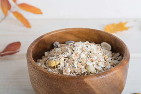 muesli, porridge in a wooden bowl decorate autumn leaves on white wood backgraund.の写真素材
