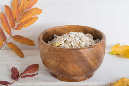 muesli, porridge in a wooden bowl decorate autumn leaves on white wood backgraund.の写真素材