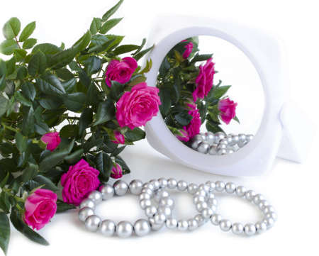 pearl bracelets, bouquet of roses and a mirror on a white backgroundの写真素材